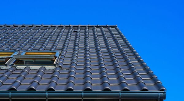 A vertical low angle closeup shot of the black roof of a building with a blue background